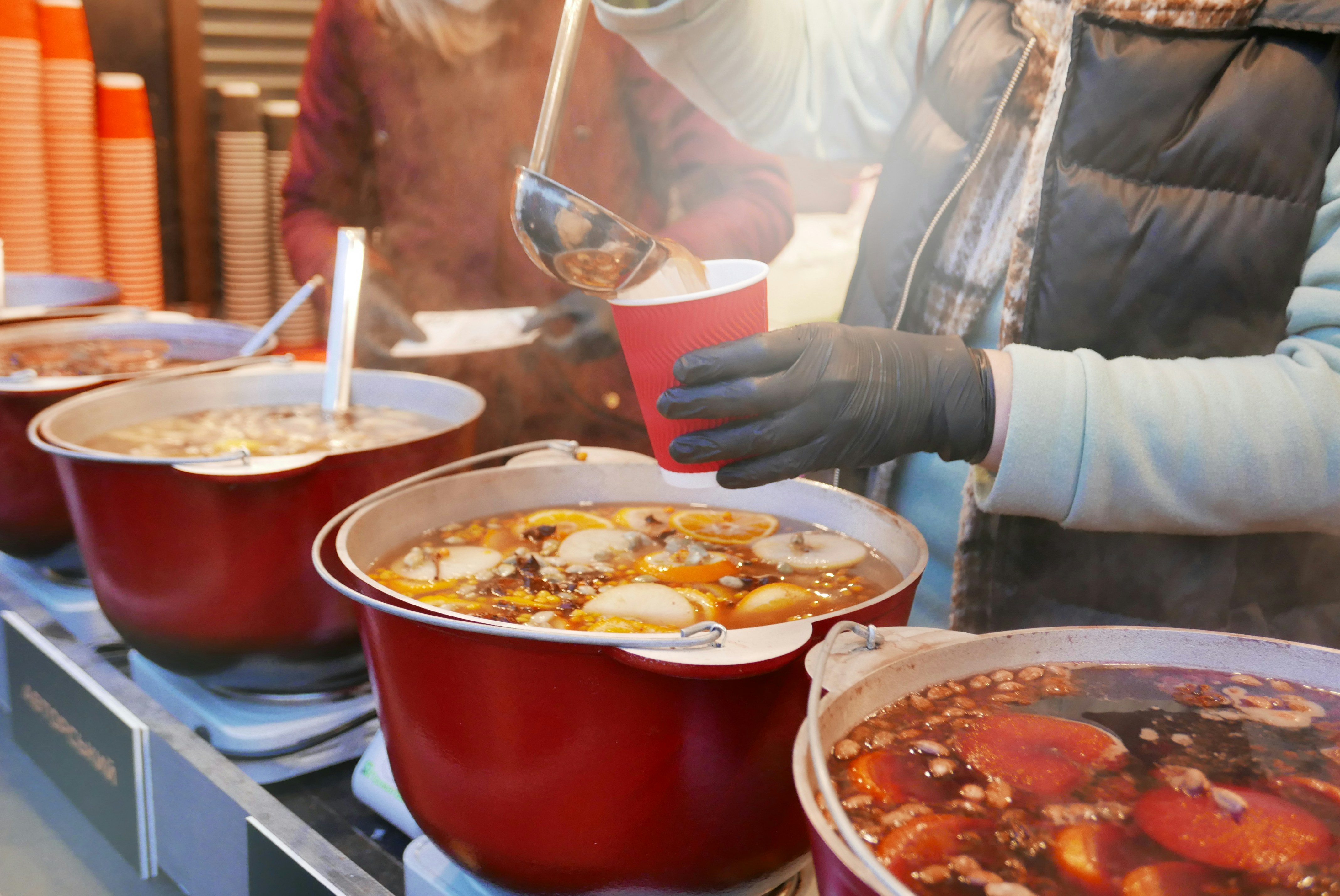 Street stall serving hot mulled wine (vin chaud) with oranges and spices at a winter market in Les Arcs, French Alps